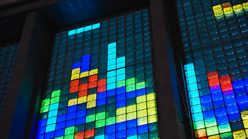 Close-up of a glass-block window lit in blue, yellow, green and red blocks
