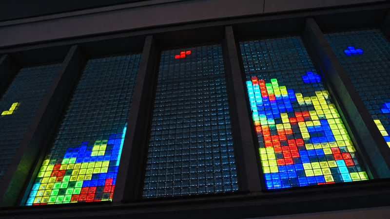 Glass-block windows seen from below, stacks of coloured blocks glowing in two of them