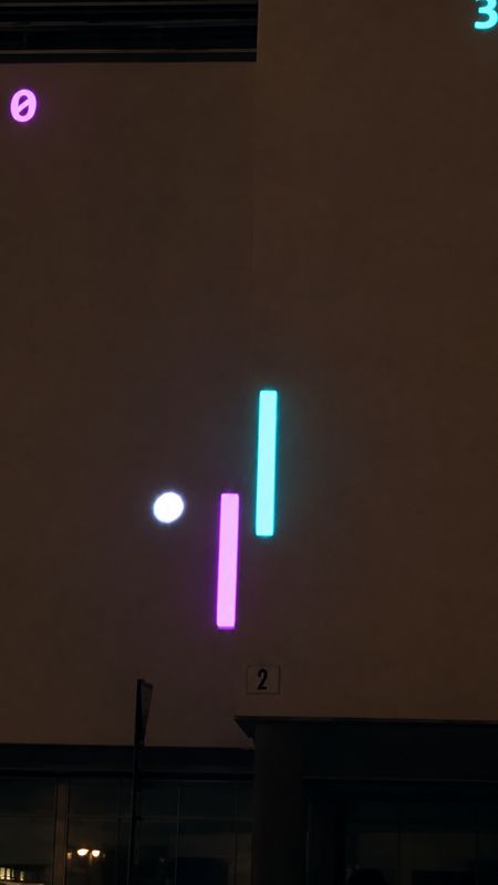 A cyan paddle, a violet paddle and a white ball projected on the facade